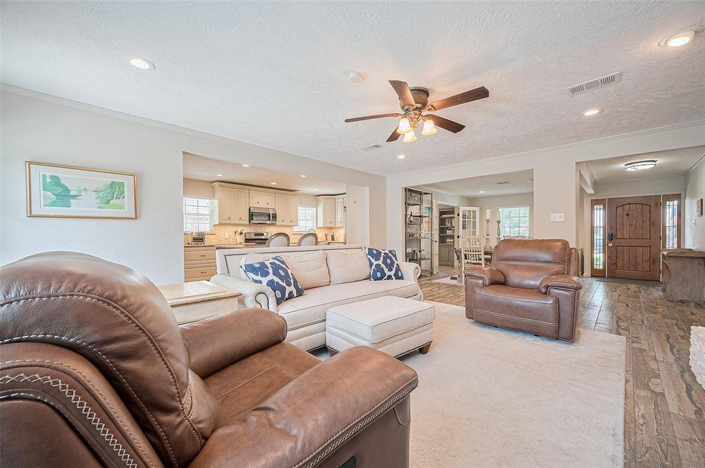 This inviting living room seamlessly connects to the kitchen and dining area, and large windows provide ample natural light. Ideal for relaxation and entertaining.