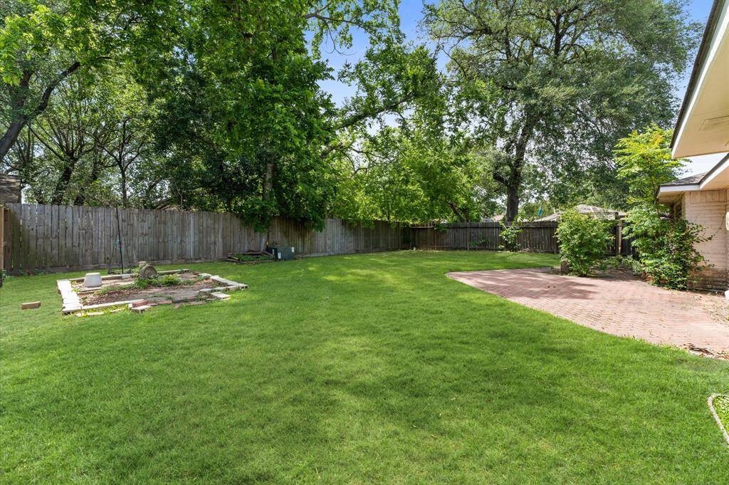 A fantastic backyard is surrounded by shade trees.