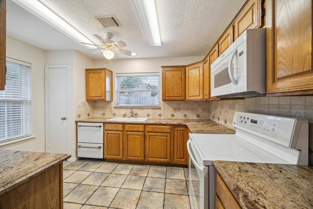 This kitchen features granite countertops and tile backsplash.