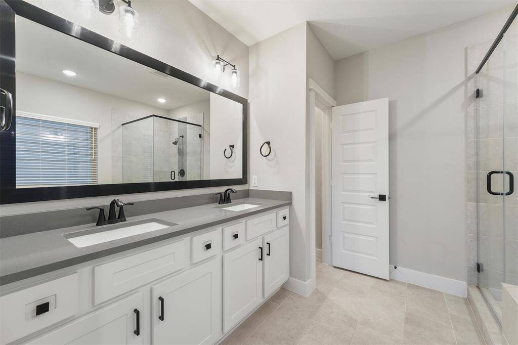 Primary bathroom with dual sinks and separate tub and walk-in shower