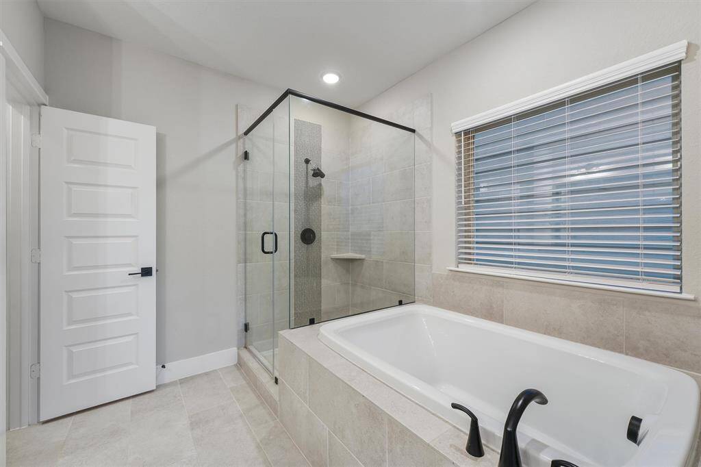 Primary bathroom with dual sinks and separate tub and walk-in shower