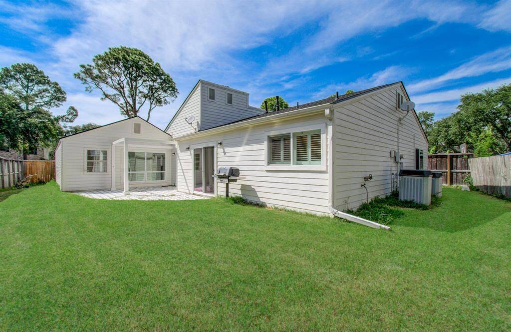 Enjoy a large backyard with lush green space and painted concrete patio, perfect for gathering and play.