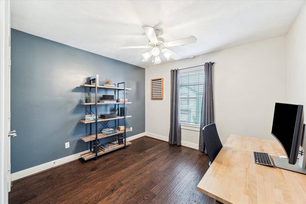 At the top of the stairs is the first bedroom which currently serves as a home office.  Lovely blue accent wall high baseboards, a ceiling fan, engineered wood floors, and a closet with double doors are here.
