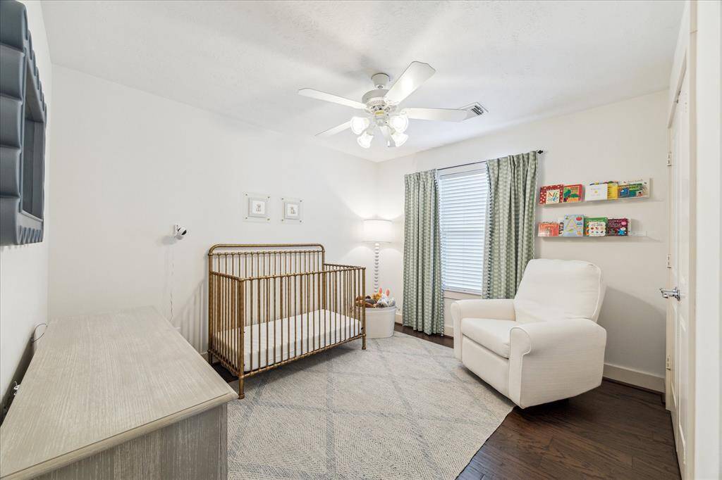 The middle bedroom upstairs has tall baseboards, engineered wood flooring, a double wide closet and ceiling fan.
