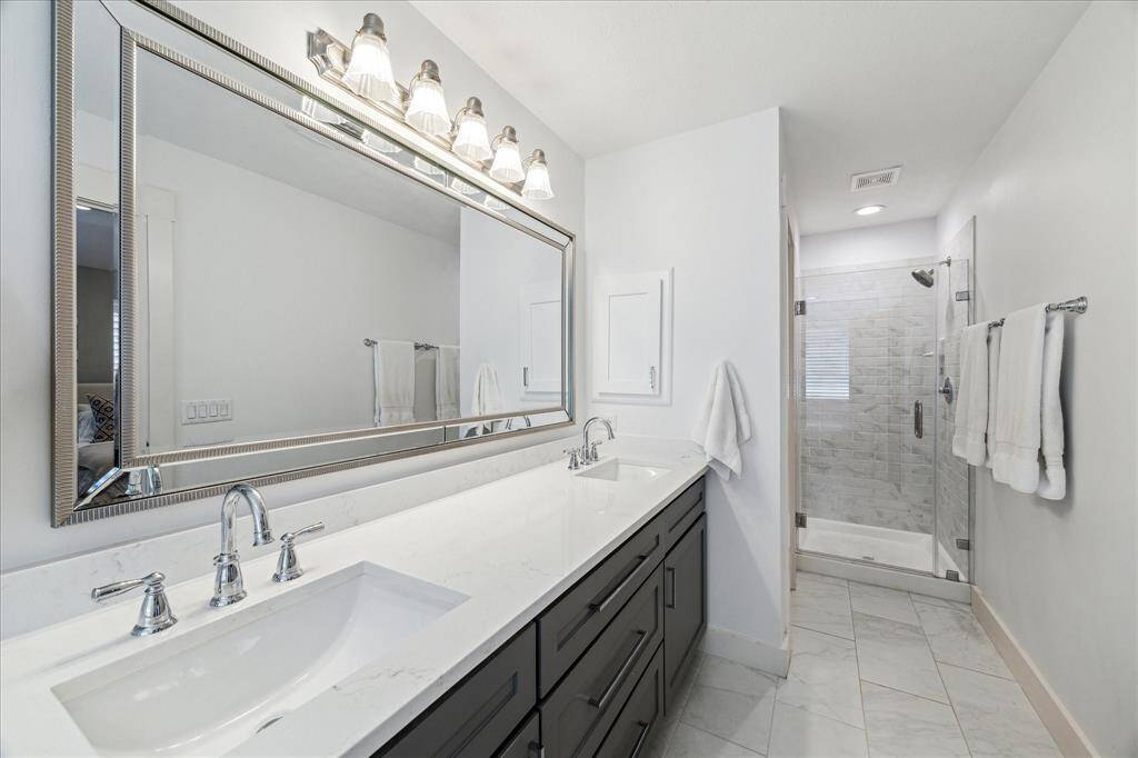 The luxurious ensuite bathroom has a separate shower with bright tile and new seamless glass door (2019).  An integrated wall cabinet for medicine or toiletries.  A separate toilet closet is to the left of the shower in this photo.