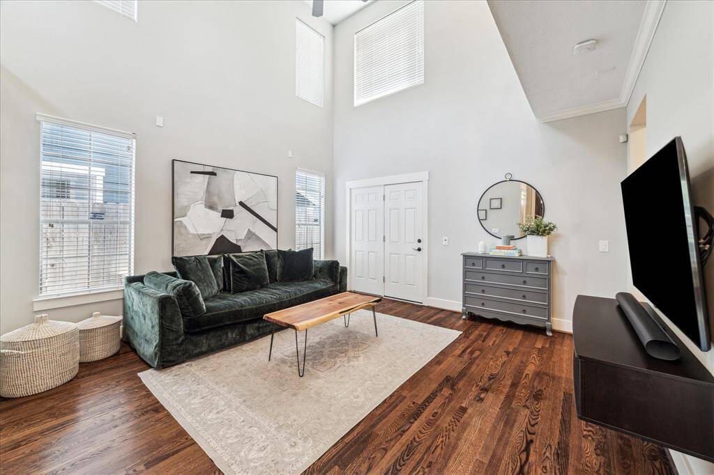 Open and airy living room has many first level windows, a soaring ceiling up to the second floor ceiling, and clerestory windows above. This is an amazing space. Solid white door leads to the covered back porch.
