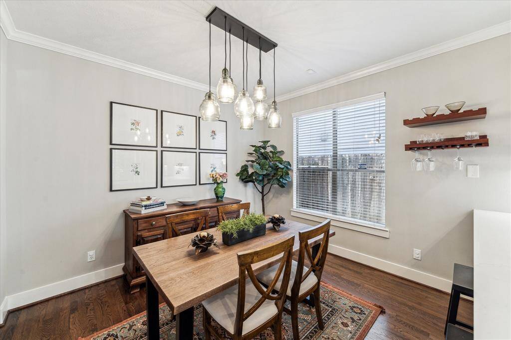 This large dining room is open to the kitchen and has a multilight modern chandelier with black accents. Notice the breakfast bar seating to the right in this photo.  Wood shelves attached to the wall stay with the property.