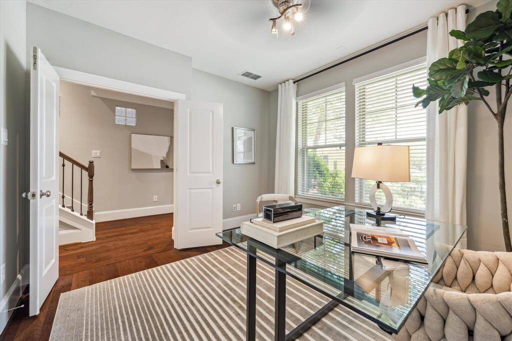 Versatile first-floor bedroom, currently used as a home office, features a double-door entry, large windows with shaded street views, modern ceiling fan, and 9-foot ceiling.