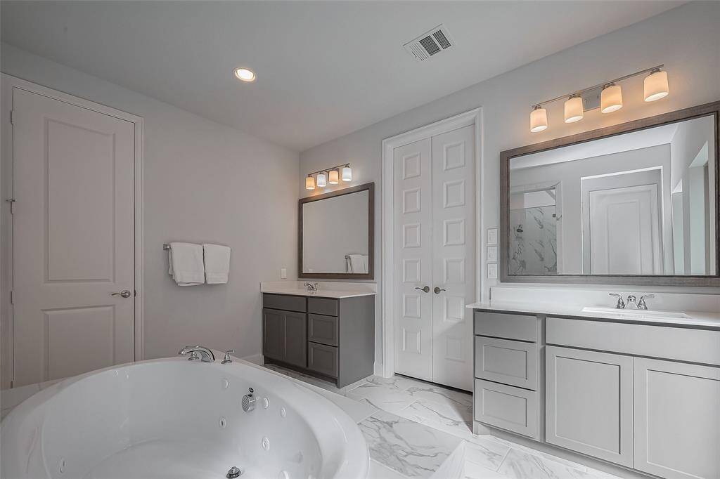 Double vanity in the primary bathroom with a water jet jacuzzi tub