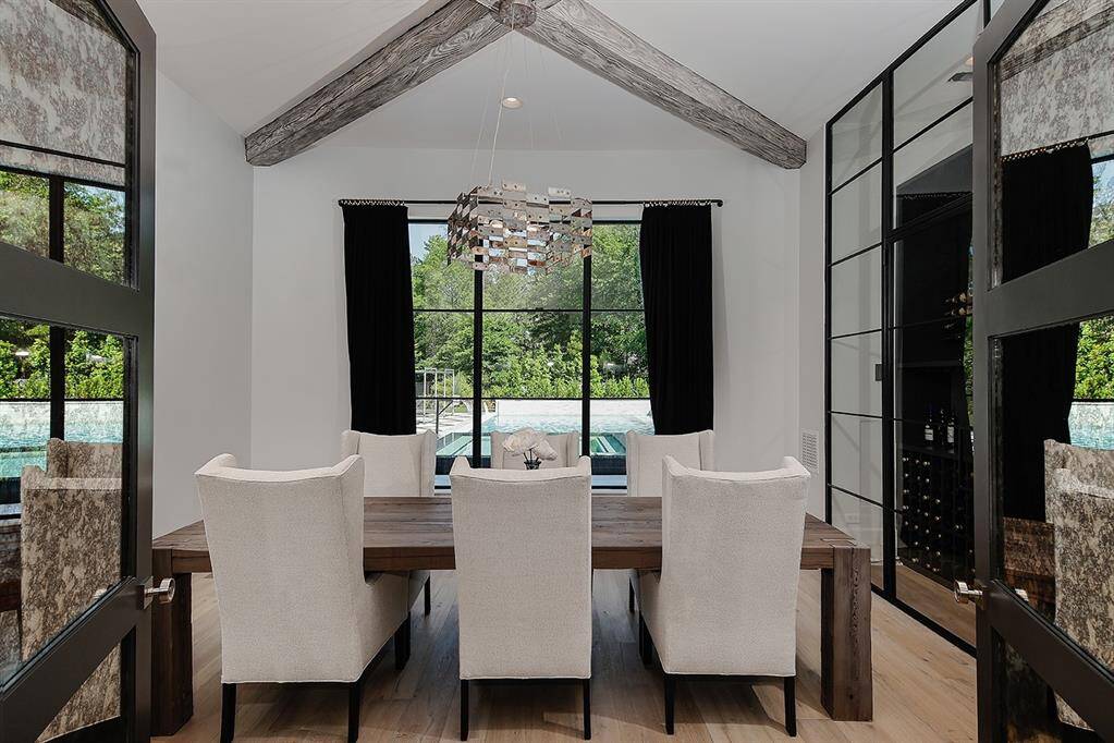 The formal dining room features a built-in wine fridge, decorative wood beam ceiling and views of the stunning pool.