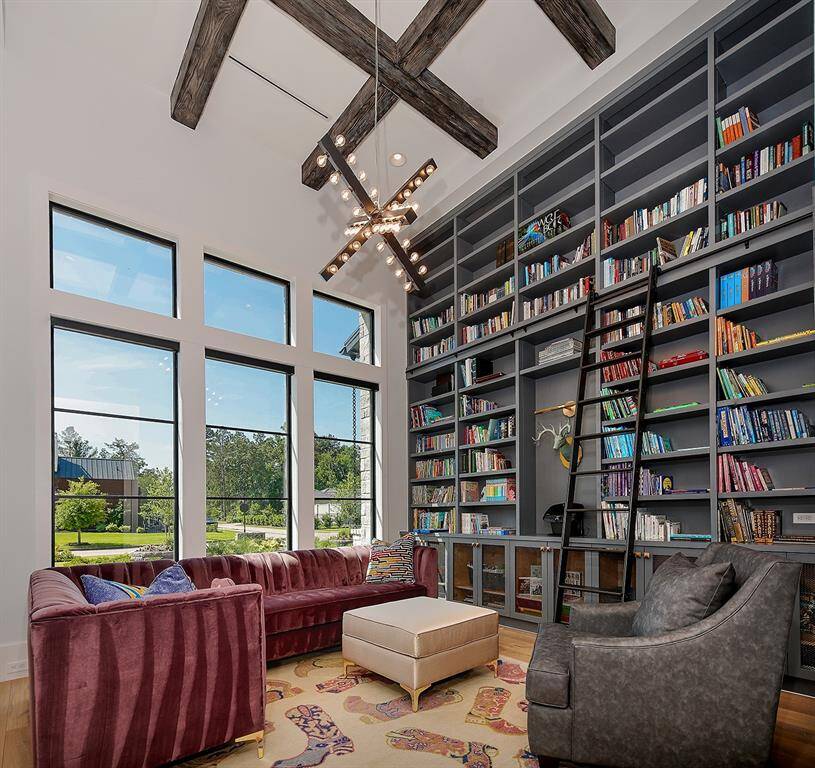 The downstairs library with custom library ladder, adjustable shelves, and enormous windows make this a relaxing and welcoming place to enjoy a good book.