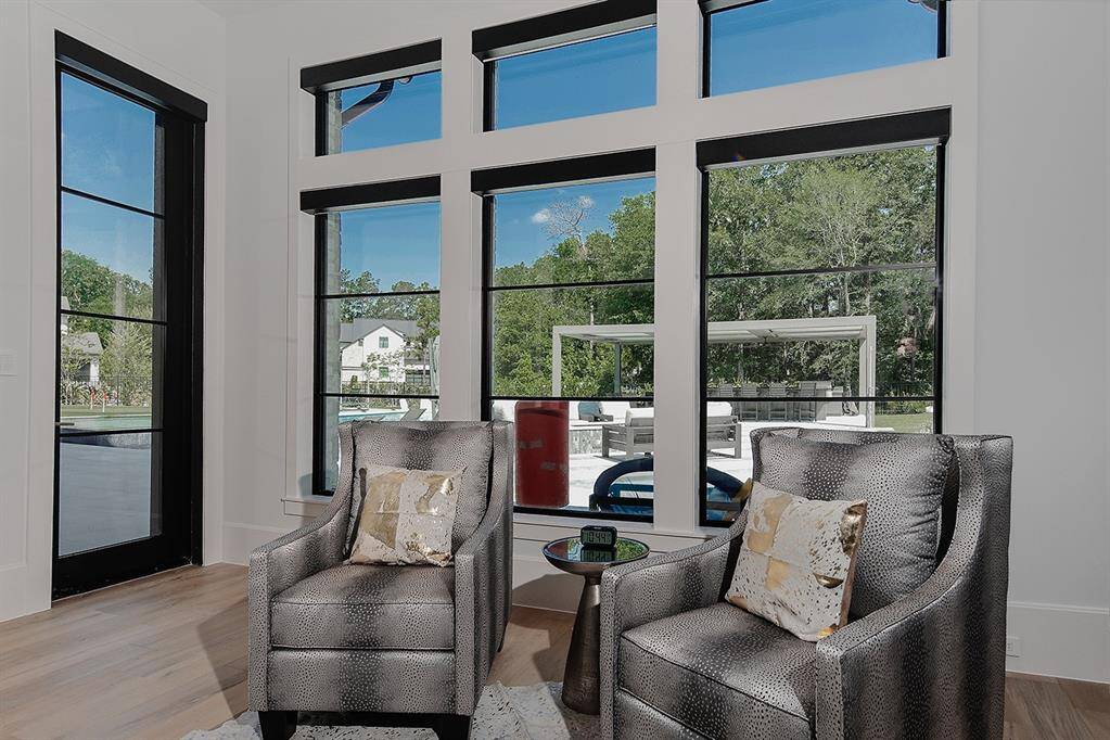 The sitting area in the primary suite, with motorized blackout shades and door leading to the patio and pool.