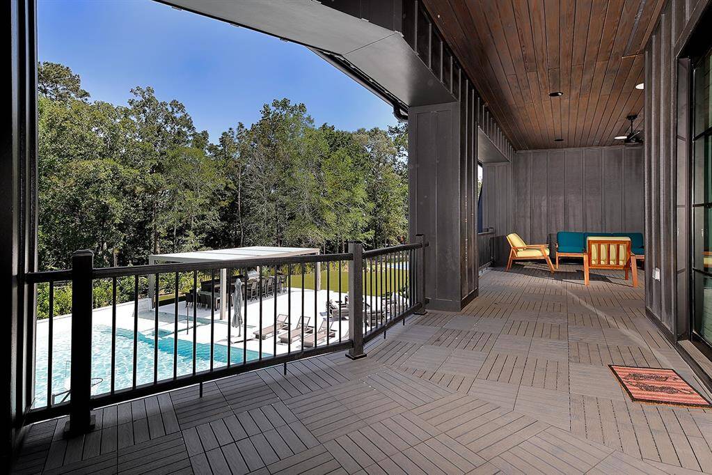 The expansive balcony upstairs has a wood ceiling and tiled floors, and offers panoramic views of the pool and beautiful trees.