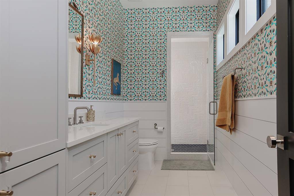 This guest bath upstairs has bead board detail and fun wallpaper and sconces!