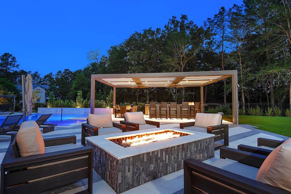 The fire pit has views of the pool and outdoor kitchen, with bar seating, SubZero and Wolf appliances.