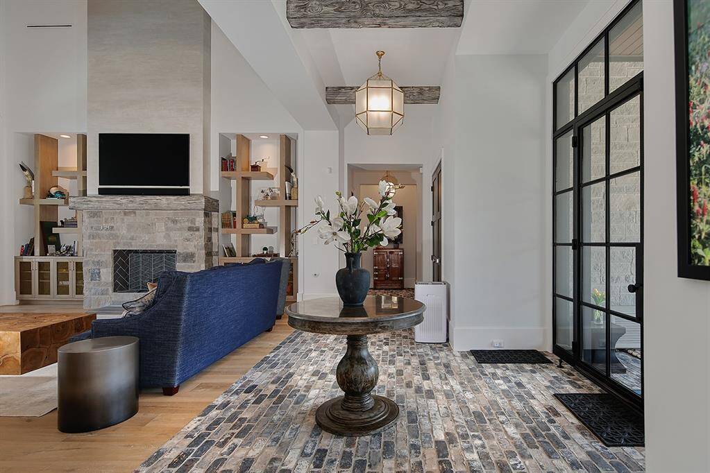 The living room, with custom plastered fireplace and stunning built-ins, offers panoramic backyard and pool views.