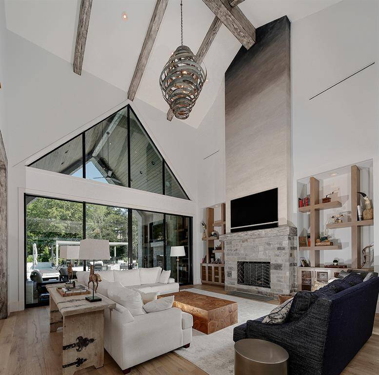 Vaulted ceiling in this breathtaking living room with custom wine barrel light fixture and access to the backyard and pool through glass and iron doors.