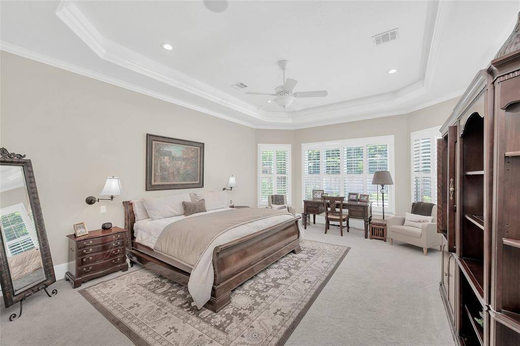 Gorgeous primary suite with tray ceilings, crown molding and bay windows overlooking the pool