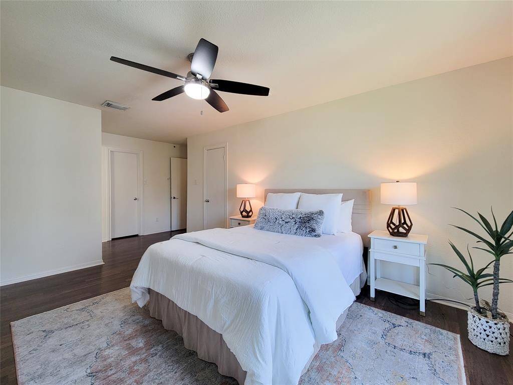 The primary bedroom has the same wood-look laminate flooring, ceiling fan, 50" TV (that stays), two walk-in closets and en suite bathroom.
