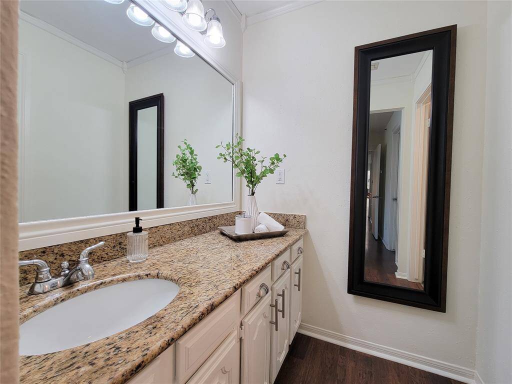En suite vanity area in the primary bedroom with granite countertop and crown molding.