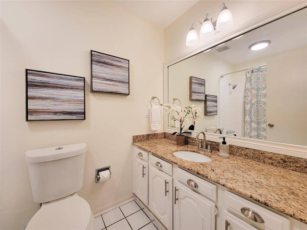 Roomy secondary bathroom with updated hardware and lighting, granite counter and shower/tub combo is located off the hallway across from the secondary bedroom.