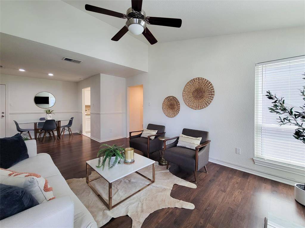 Reverse view of the living room showing the open dining area, private door to the garage, kitchen and entry area on the right.
