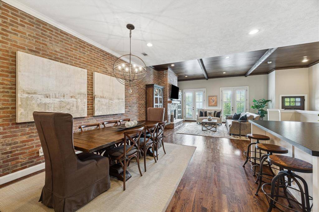 Enjoy effortless entertaining in this airy and inviting great room, where warm hardwoods, exposed brick, and wood-beamed ceilings create a cohesive and welcoming flow.