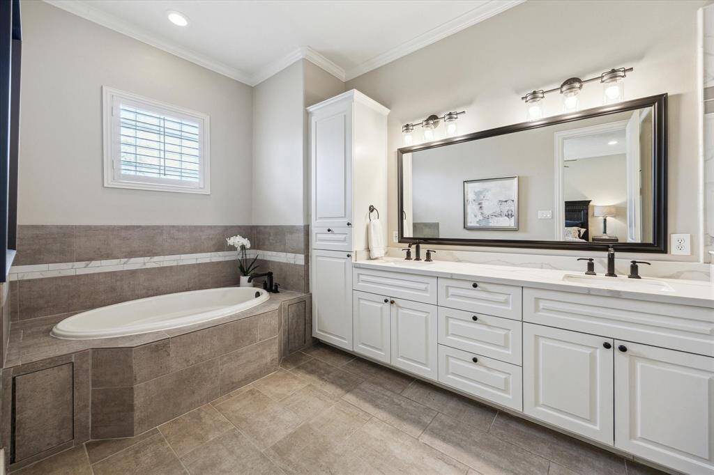 The spa-inspired primary bath features a deep soaking tub, dual vanities with ample storage, and elegant tilework—creating a serene retreat to start or end your day.