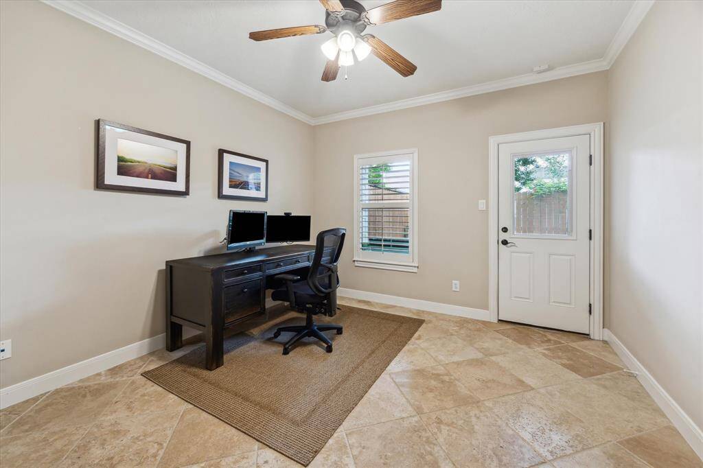 Spacious downstairs bedroom featuring neutral tones, crown molding, and a large window with plantation shutters—perfect for guests.