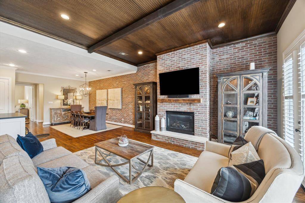 A striking brick accent wall and custom built-ins frame the living and dining spaces, creating a perfect balance of charm, texture, and functionality.