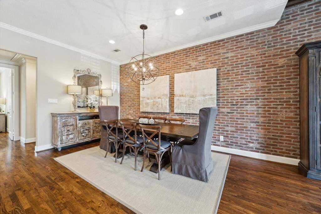 Gather in style in the elegant dining room, where a striking brick accent wall and statement lighting create a warm, inviting space for hosting.
