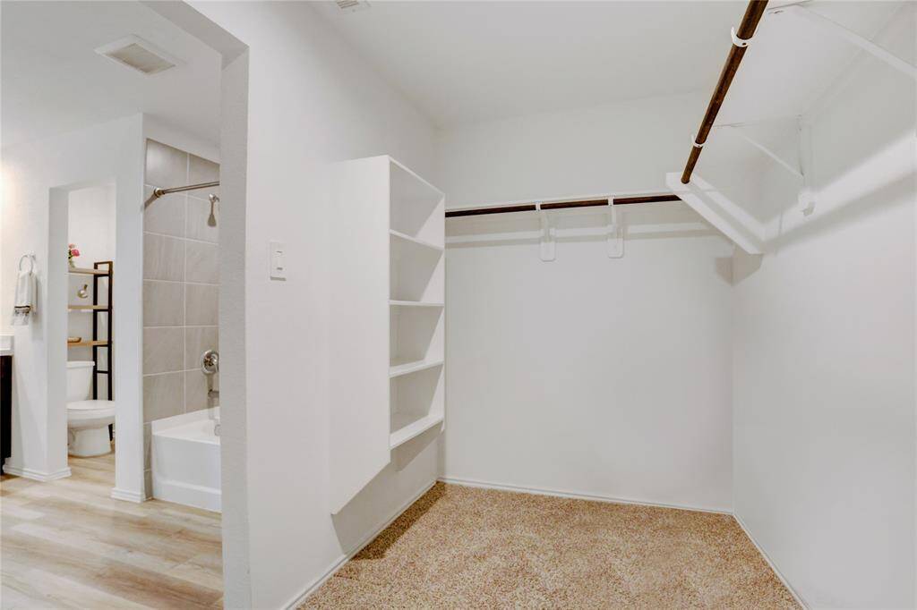 The full-entry closet in the en suite is carpeted and thoughtfully designed with built-in shelving, hanging rods, and ample room to stay organized.