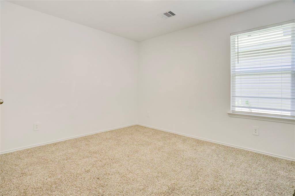 This carpeted bedroom features a soothing palette and a large window that brings in plenty of light. It’s ready to become a peaceful retreat, workspace, or creative studio.