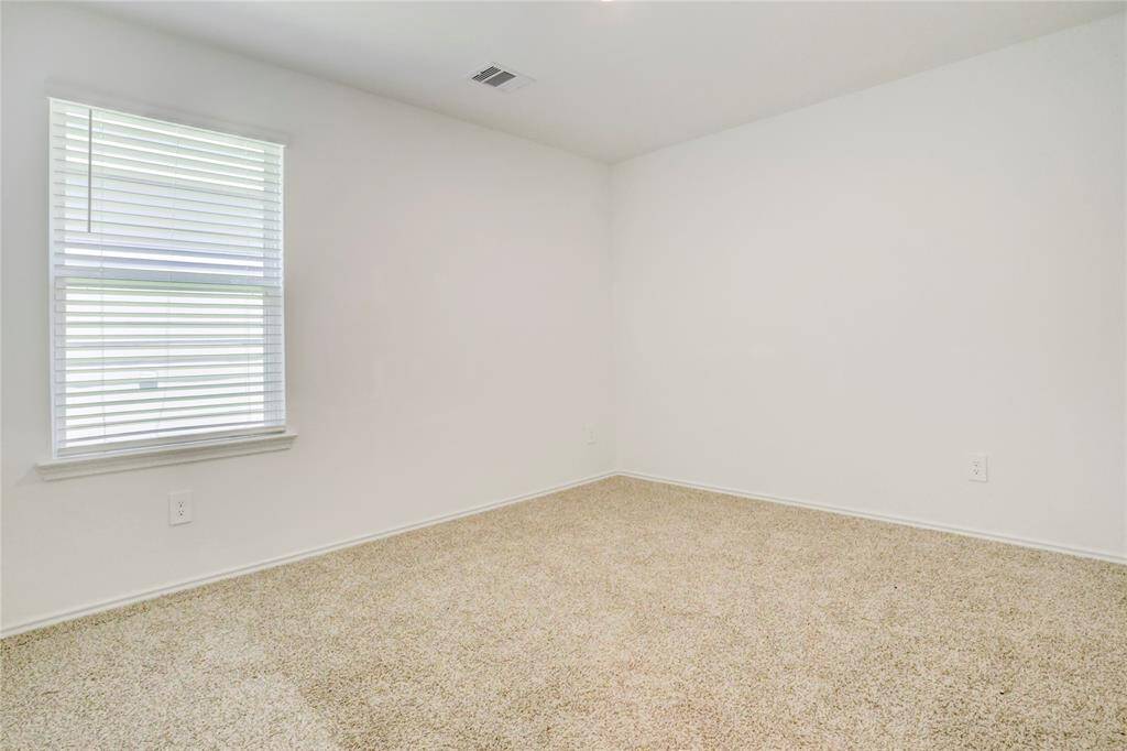 Nearly identical to the previous, this additional bedroom offers soft carpeting, a wide window, and the same light color scheme.