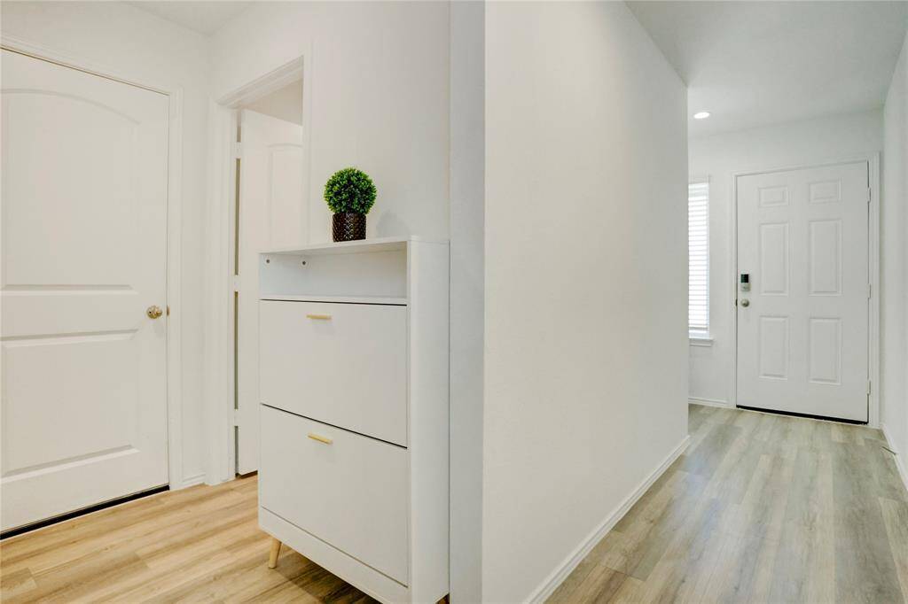 From inside, the front door is positioned next to a window that brightens the space. A nearby storage cabinet provides a perfect spot for shoes or entryway essentials.