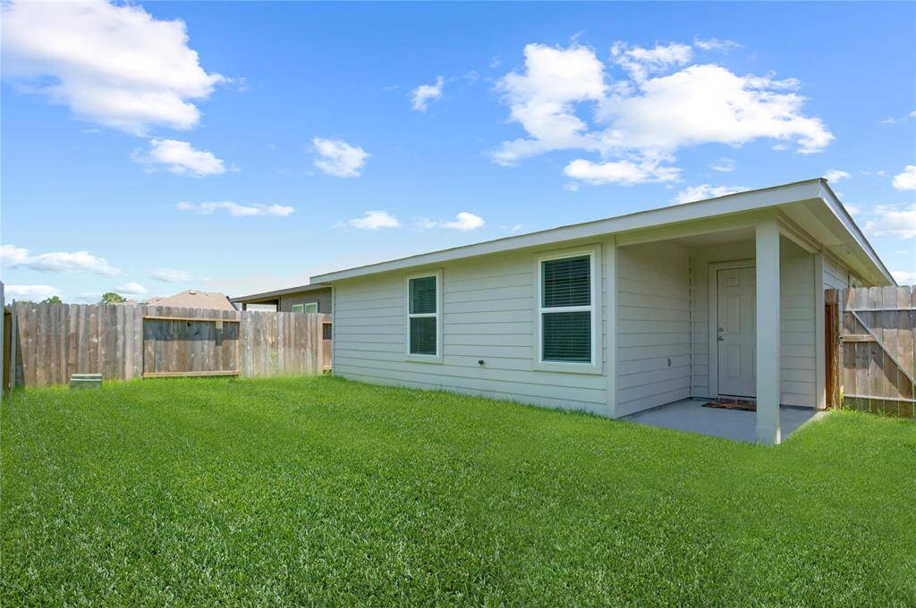 Out back, the small covered patio is ideal for enjoying a morning coffee or evening breeze while overlooking the lush backyard.