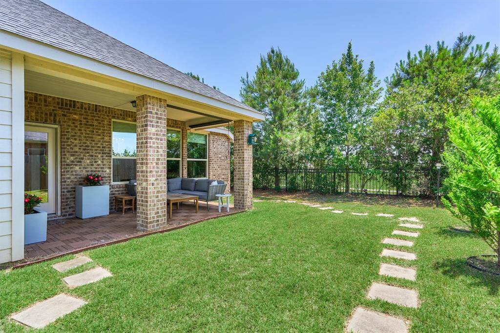 Backyard overlooks serene greenbelt with wrought iron fencing detail and treeline for privacy.