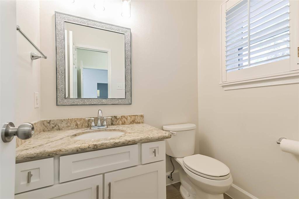 The half bathroom is located on the first floor with granite counters, a framed mirror and updated Shaker Style cabinetry faces.