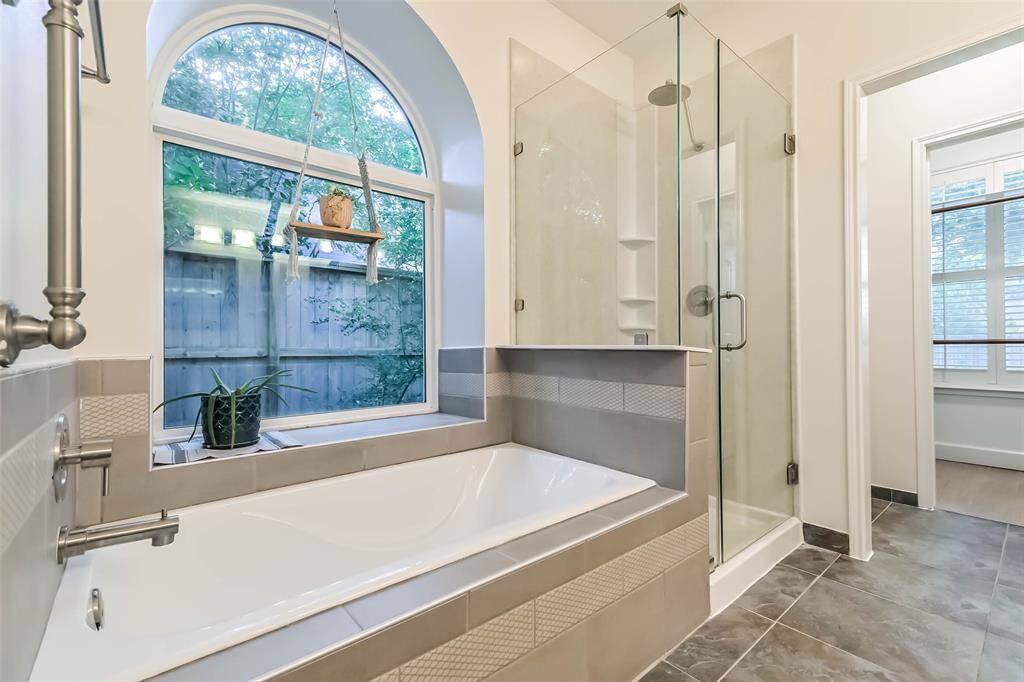 There is a soaking tub and separate standing shower with tile surround and seamless glass door in the primary bathroom.