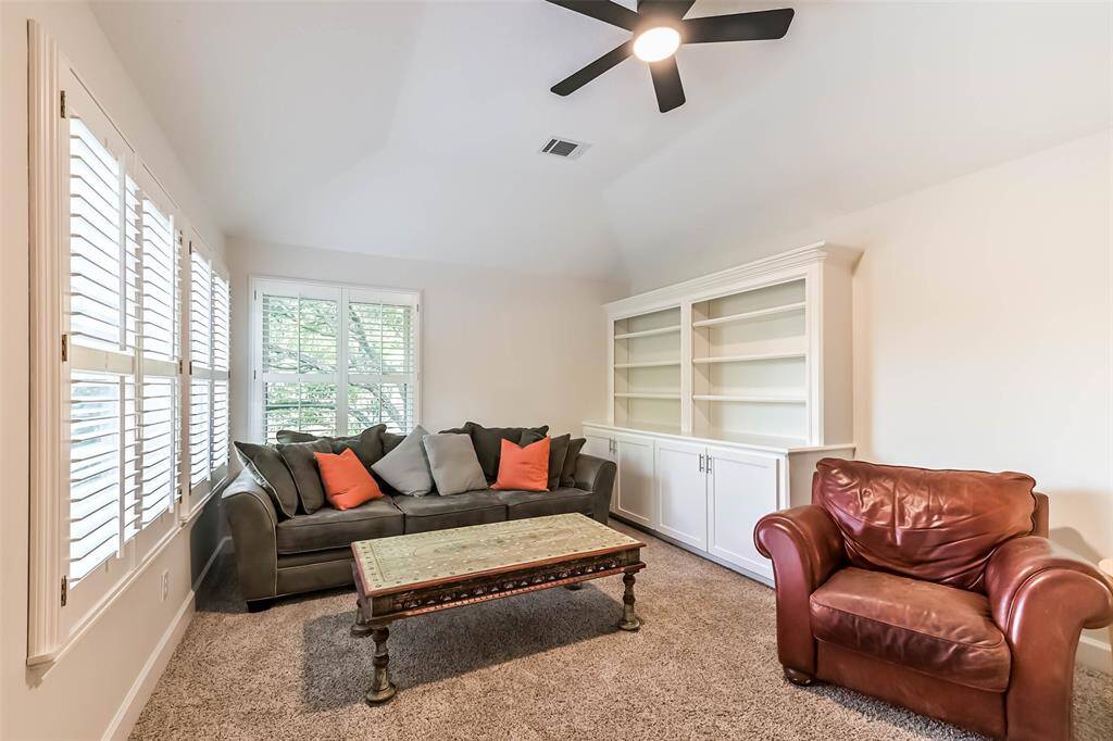 Upstairs is the game room that showcases an updated ceiling fan, built-ins with new cabinet faces and plantation shutters.