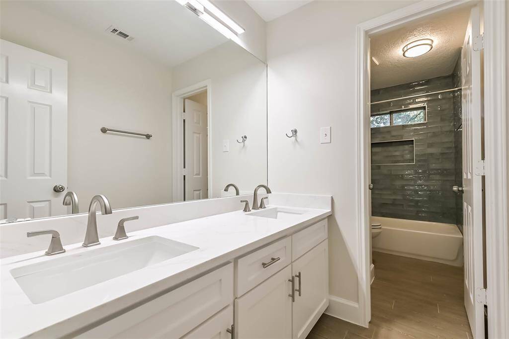 The second full bathroom is located upstairs and was just remodeled in May 2025. It features tile floors, quartz counters, double sinks, updated cabinetry faces and a tub+shower duo with designer tile surround.