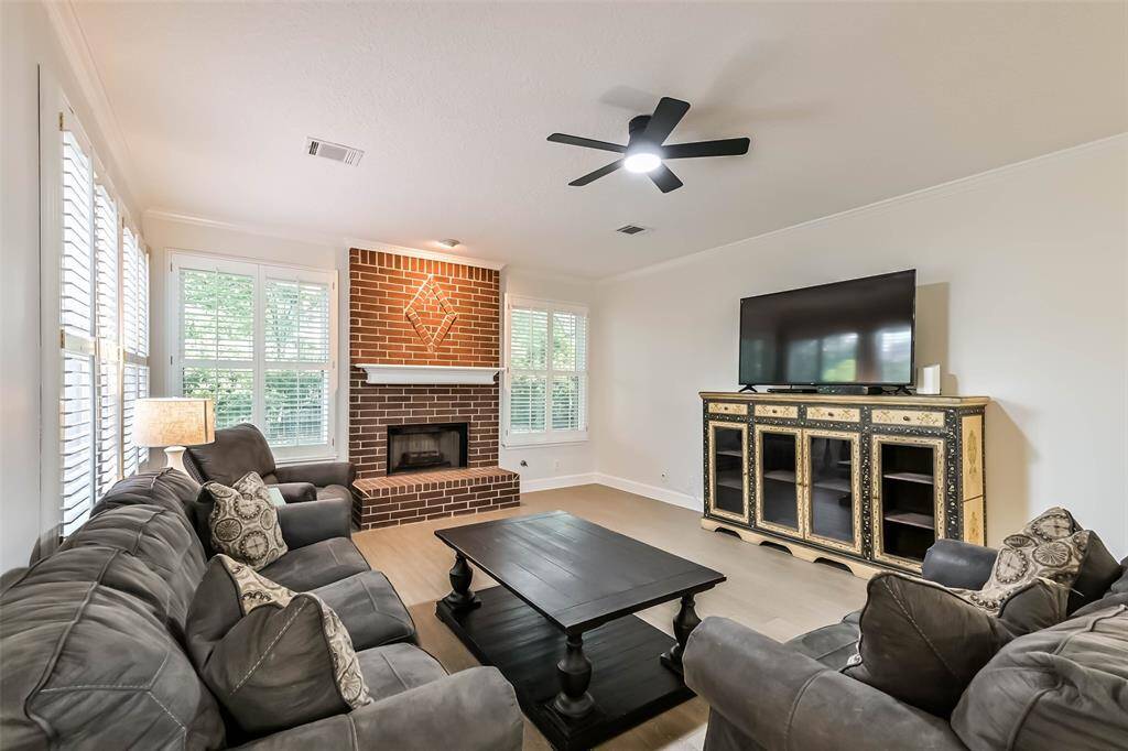 The living room features an updated ceiling fan, crown molding, gas connection fireplace and plantation shutters.