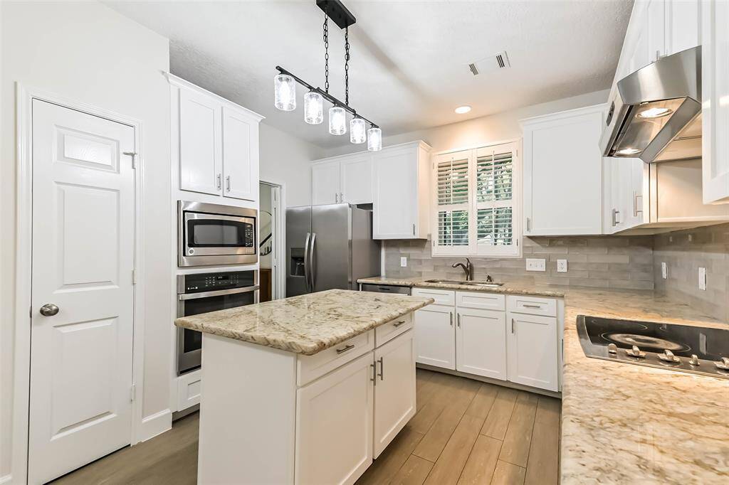 The island kitchen showcases granite counters with tile backsplash (2025), SS appliances, updated light fixture (2025) and a pantry.