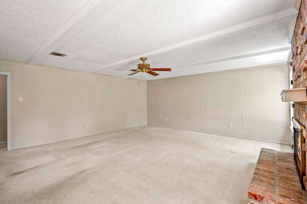 Full of charm and character, this family room offers a gas fireplace, wood beam accents, built-in shelves, and large windows overlooking the backyard.
