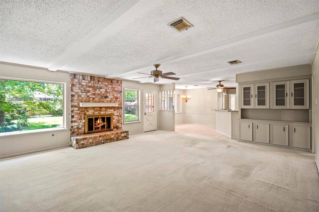 Full of charm and character, this family room offers a gas fireplace, wood beam accents, built-in shelves, and large windows overlooking the backyard.