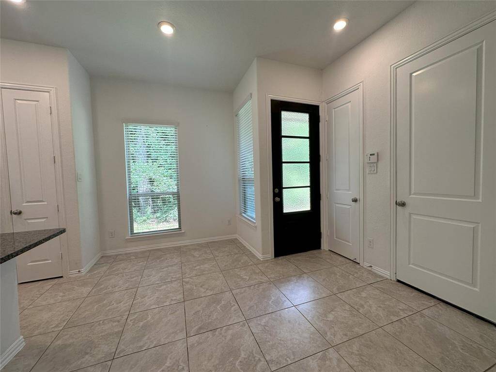 Bright entryway with modern tile flooring, a window bringing in natural light, and a sleek door with glass panels. Ideal for a welcoming atmosphere.