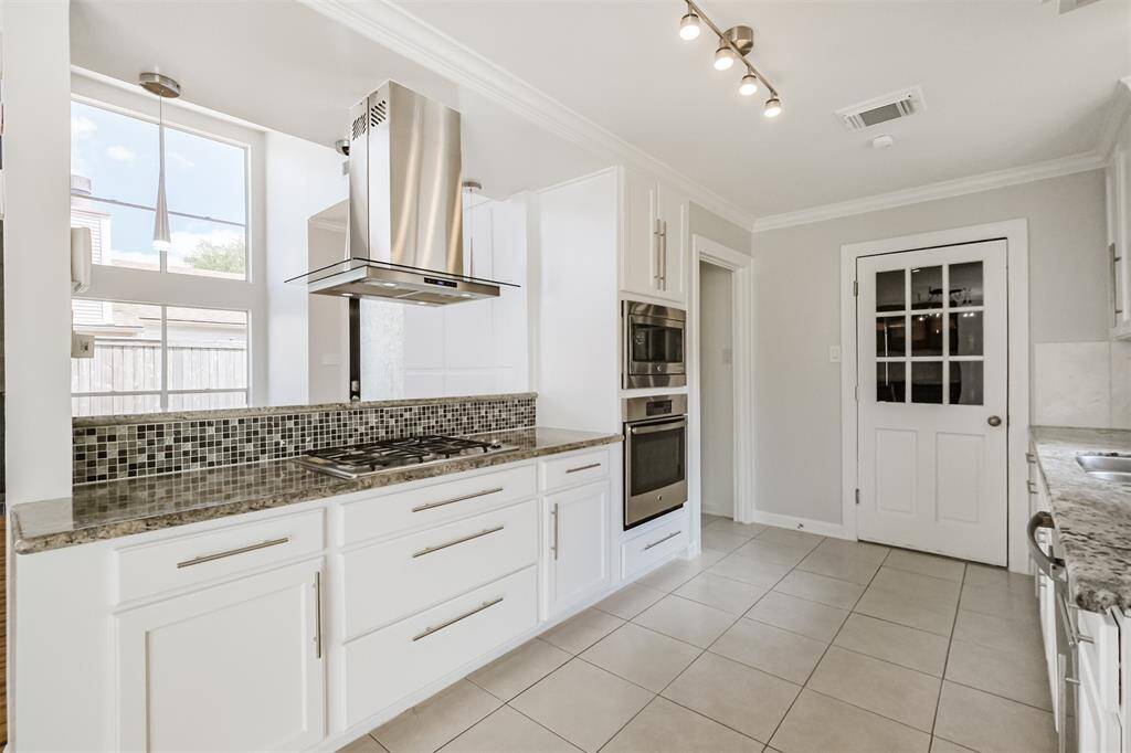 The kitchen features granite counters with tile backsplash, updated cabinetry, crown molding and SS appliances.