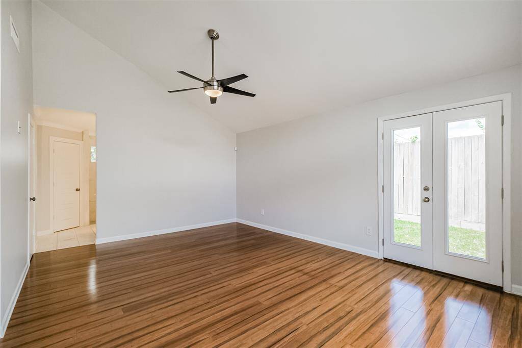 The spacious primary bedroom has laminate floors, high ceilings an updated ceiling fan and access to the backyard through the French doors.