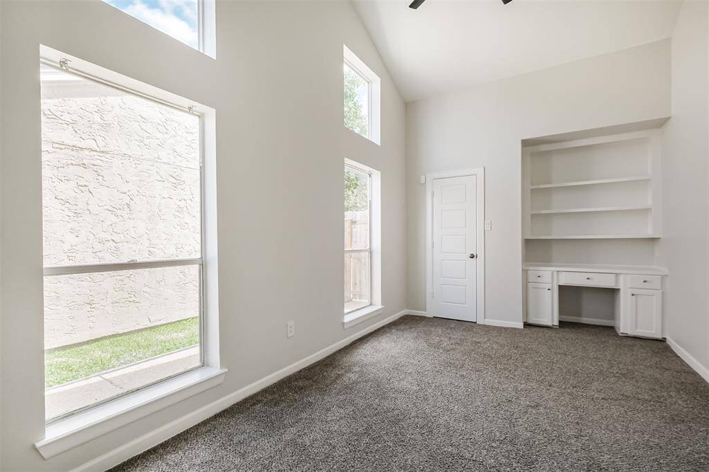 The second bedroom has carpet floors (2023), high ceilings, a walk-in closet, ceiling fan and built-in desk and shelves.