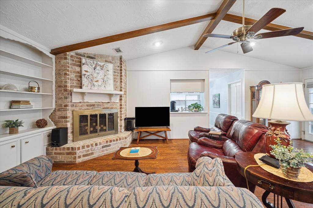 Great view of the Fireplace and brick hearth, built-in cabinetry, laminate flooring, and openness of the Family Room.